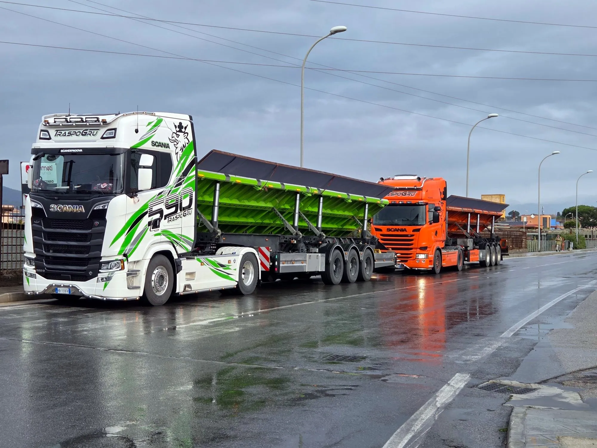 Scania con semirimorchi a piano inclinato carichi, su strada bagnata